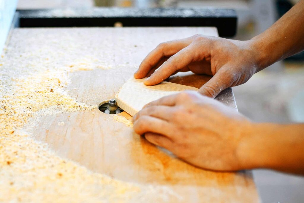 hands shaping a wooden board on a router table for a handmade valentine gift
